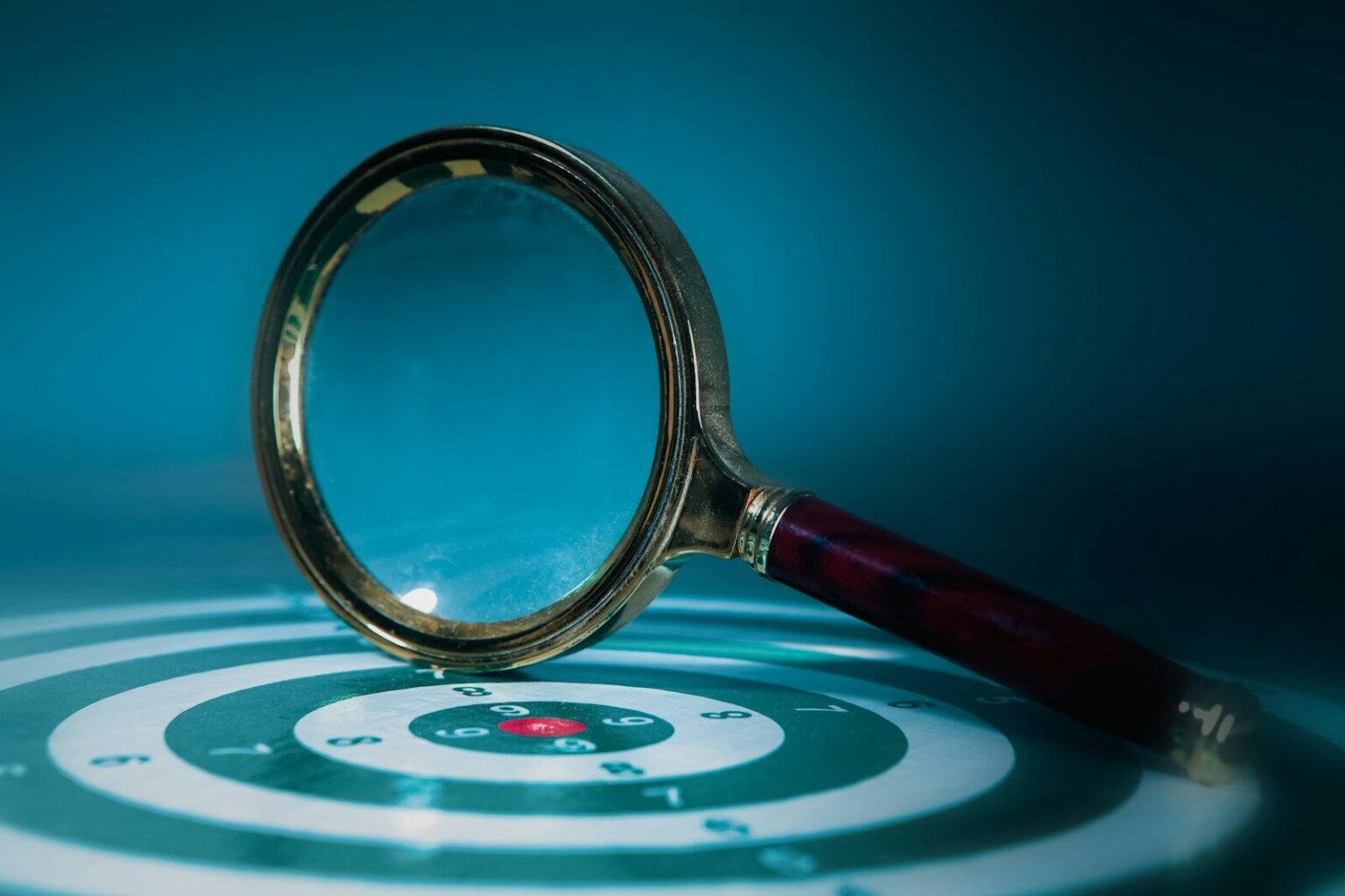 Magnifying glass over a target with bullseye.