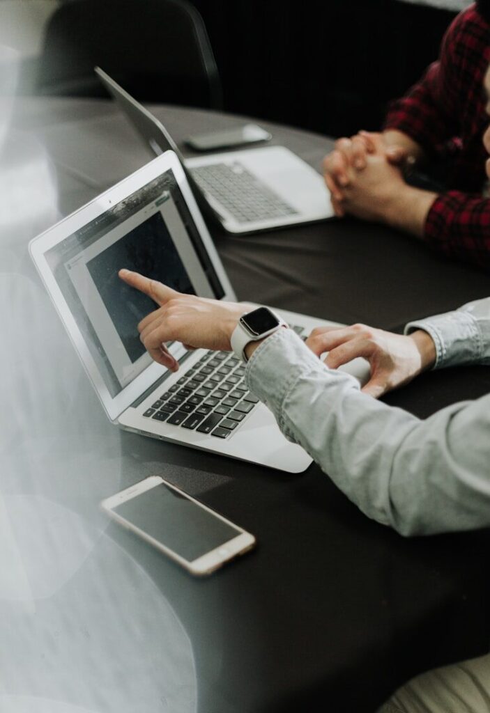 two people sitting at a table with laptops